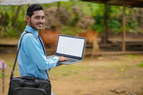 Young indian agronomist or banker showing laptop screen photo