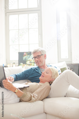 Older couple relaxing together on living room sofa © KOTO