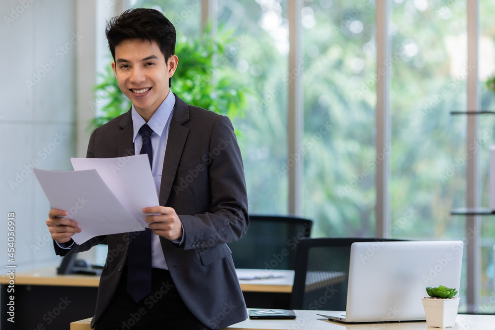 Glad Asian manager working with papers in office Glad Asian manager working with papers in office