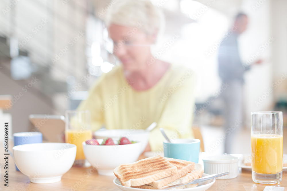 Older woman using digital tablet at breakfast table Older woman using digital tablet at breakfast table