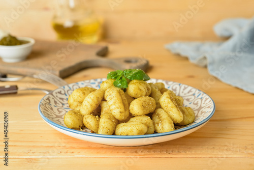 Plate with tasty pesto gnocchi on wooden background