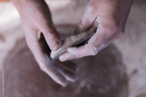 Vertical photo of dirty hands working with clay