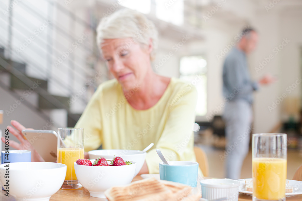 Older woman using digital tablet at breakfast table Older woman using digital tablet at breakfast table