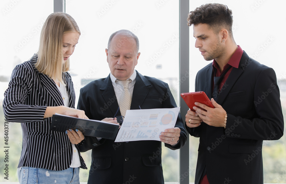 Portrait of adults caucasian 2 businessmen and 1 businesswoman between manager and staff are talking and seeing report paper. Businessman holding tablet and eyeglass during a meeting on morning day Portrait of adults caucasian 2 businessmen and 1 businesswoman between manager and staff are talking and seeing report paper. Businessman holding tablet and eyeglass during a meeting on morning day