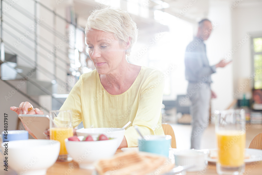 Older woman using digital tablet at breakfast table Older woman using digital tablet at breakfast table