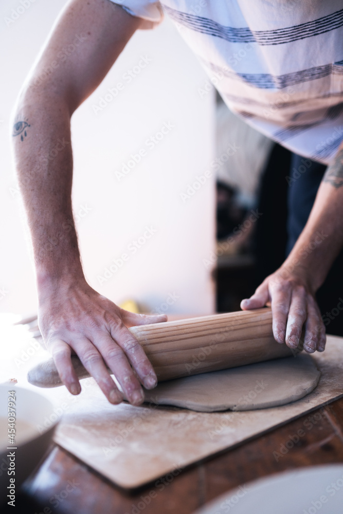Man doing pottery at home. Close up of hands using clay roller Man doing pottery at home. Close up of hands using clay roller