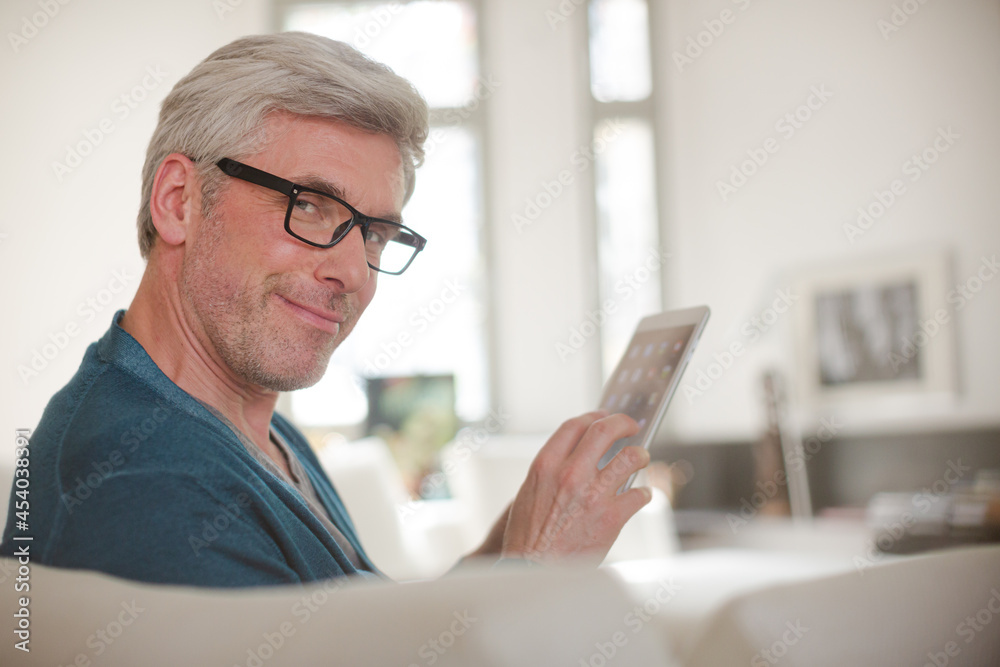 Older man using digital tablet on living room sofa Older man using digital tablet on living room sofa
