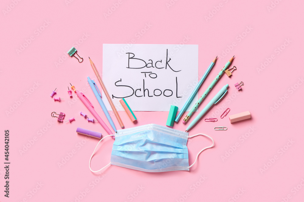 Paper with text BACK TO SCHOOL, stationery and medical mask on color background Paper with text BACK TO SCHOOL, stationery and medical mask on color background