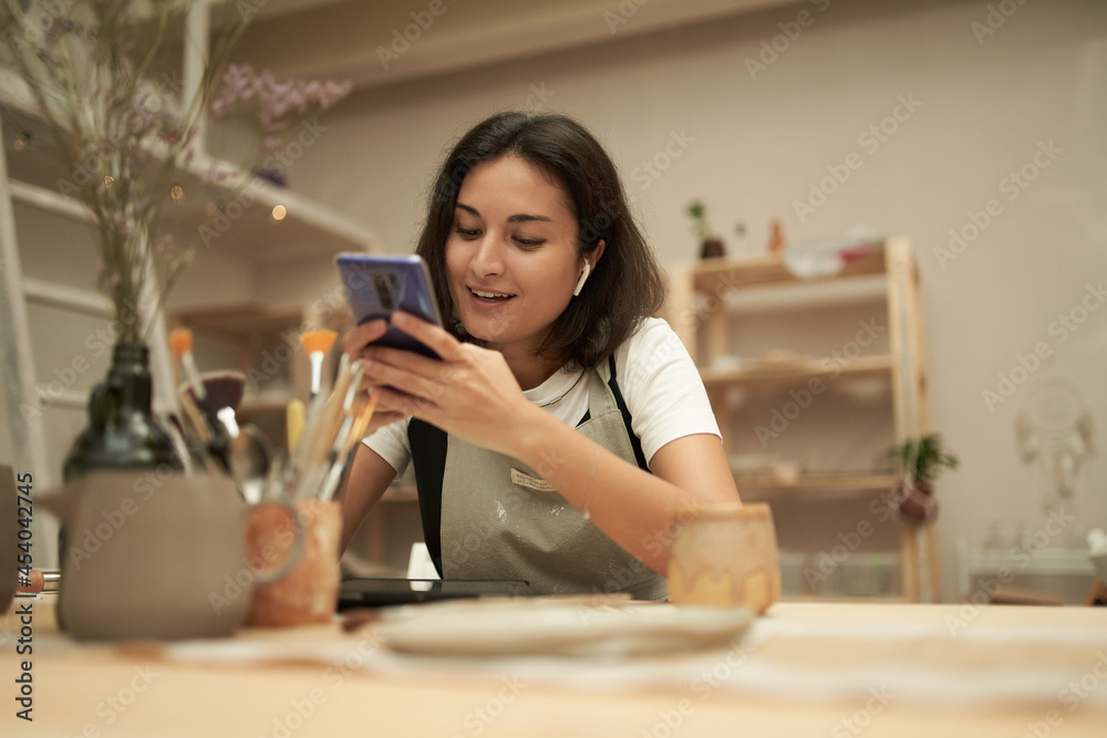 © Sergey - Happy craftswoman texting on smartphone © Sergey - Happy craftswoman texting on smartphone