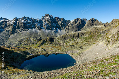 Fototapeta Naklejka Na Ścianę i Meble -  A pond in the valley and the soaring peaks of the mountains sprinkled with the first autumn snow. The Great Cold Valley (Dolina Starolesna, Velka Studena dolina). Tatra Mountains. Slovakia.