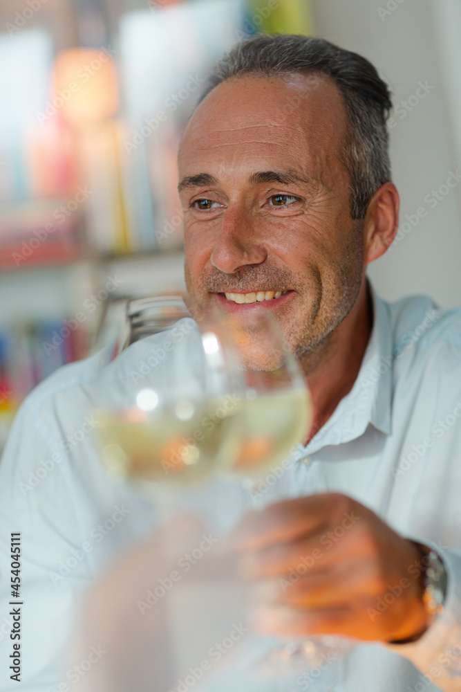 Older man drinking white wine at dinner
