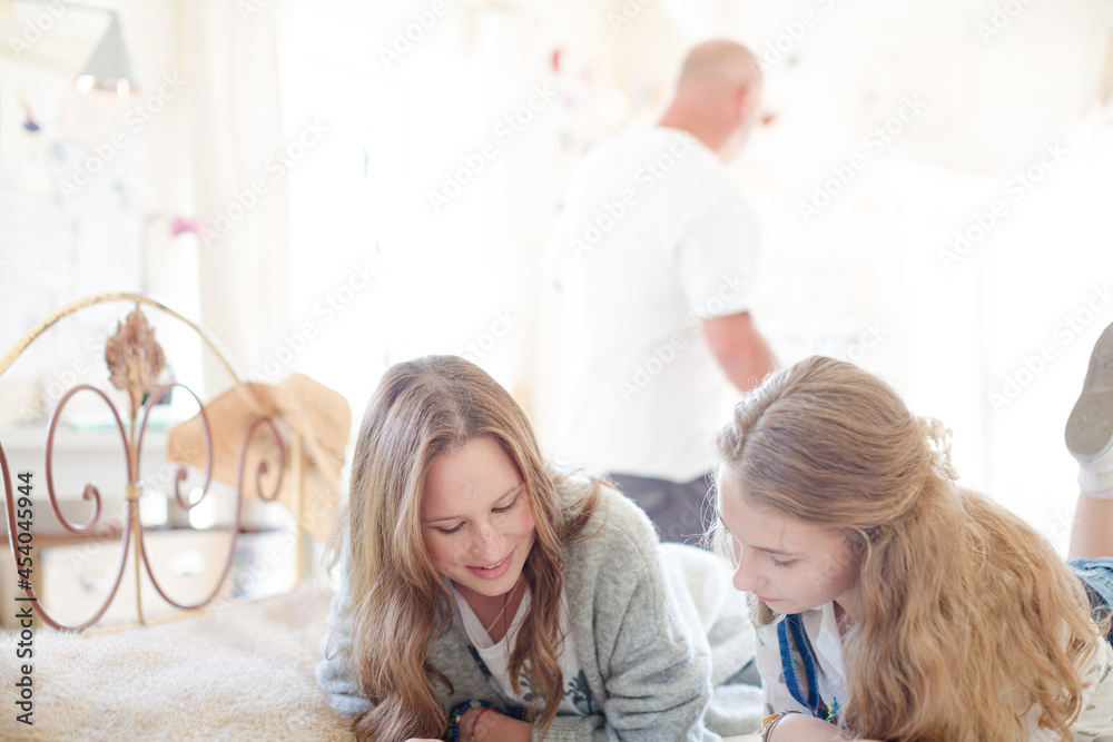 Fototapeta premium Two teenage girls on bed writing in notepads