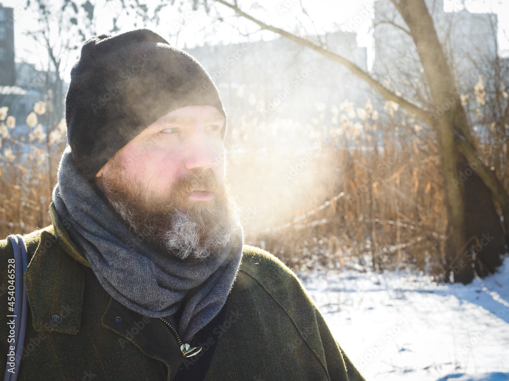 Fotografie Man breathe out cold winter air in a park