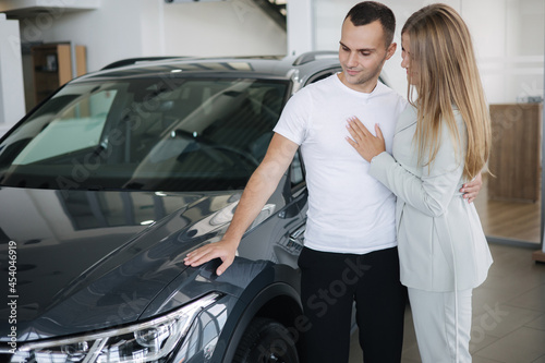 Portrait of beautiful young couple happy after buying new car from car showroom. Woman hus her man and glad © Aleksandr