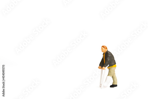 Miniature people , Full length view of a man with broken leg is using crutch on white background.