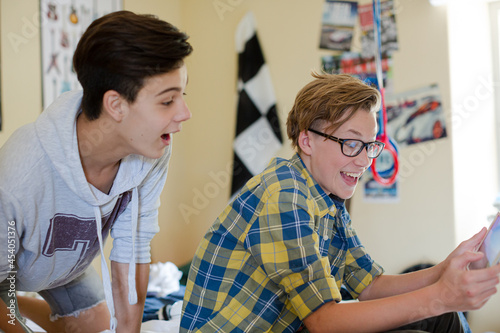 Two teenage boys having fun while using digital tablet