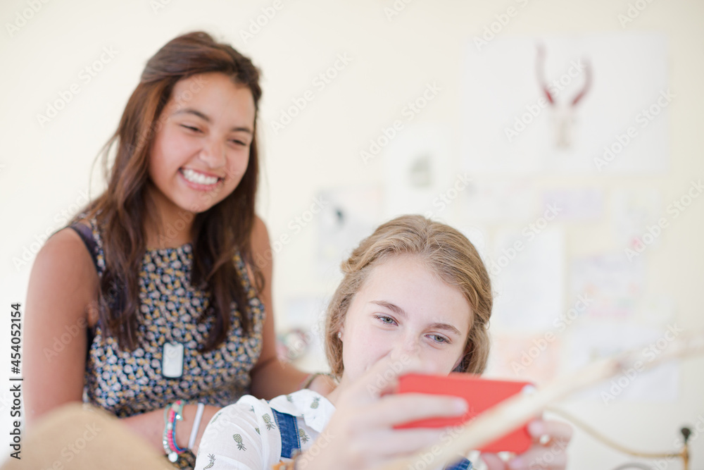 Two teenage girls sharing smart phone and smiling Two teenage girls sharing smart phone and smiling