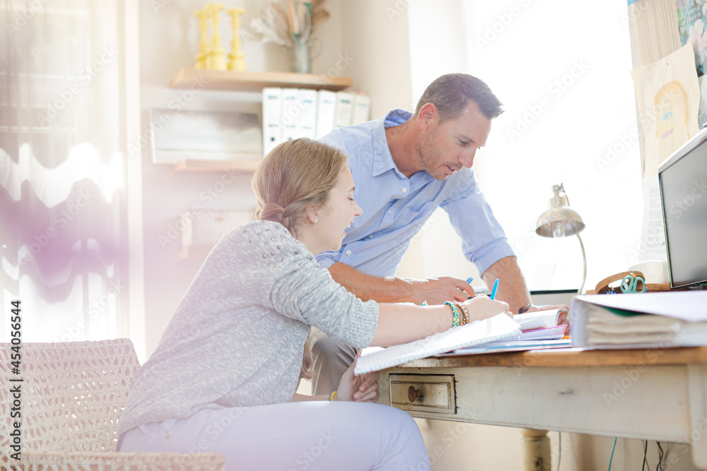 Father helping teenage daughter with her homework Father helping teenage daughter with her homework