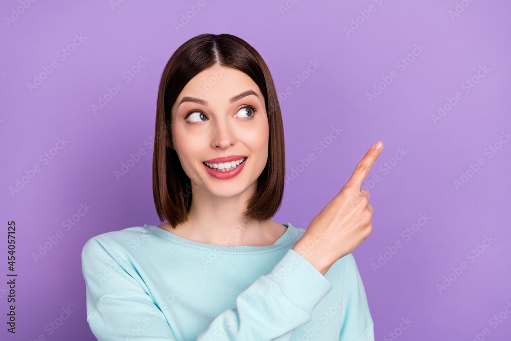 Photo portrait girl wearing blue pullover showing finger empty space isolated pastel violet color background Photo portrait girl wearing blue pullover showing finger empty space isolated pastel violet color background