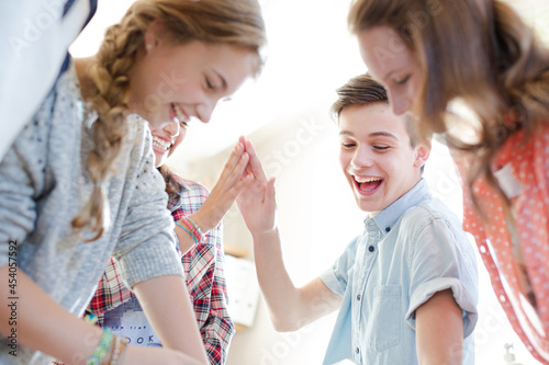 Group of teenagers doing high five in living room