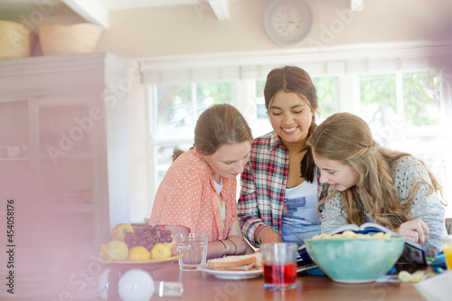 Teenage girls learning at table in kitchen