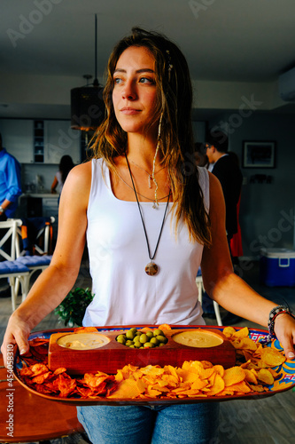 Young woman looking away while carrying tray of food during reunion at home