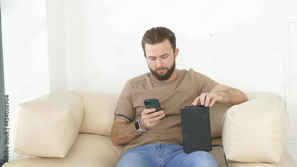 Man turning on wireless smart column with the use of smartphone. Concept of a smart home wireless devices. Man turning on wireless smart column with the use of smartphone. Concept of a smart home wireless devices.