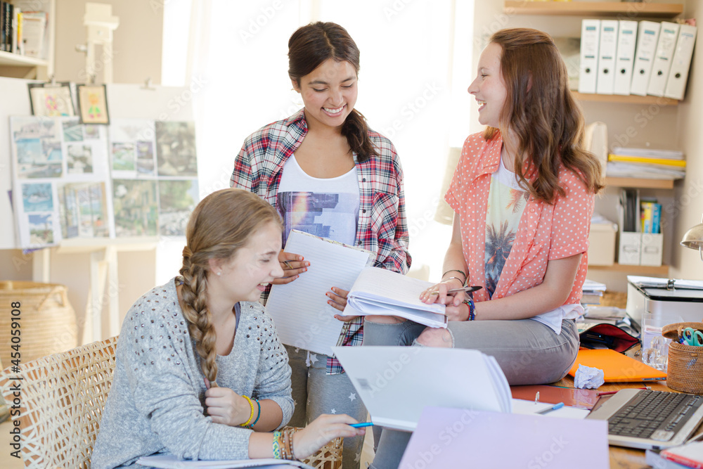Three teenage girls doing homework in room Three teenage girls doing homework in room