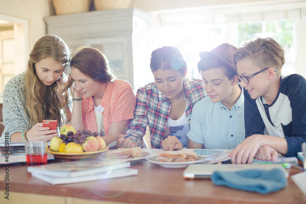 Group of smiling teenagers gathered around table in dining room Group of smiling teenagers gathered around table in dining room