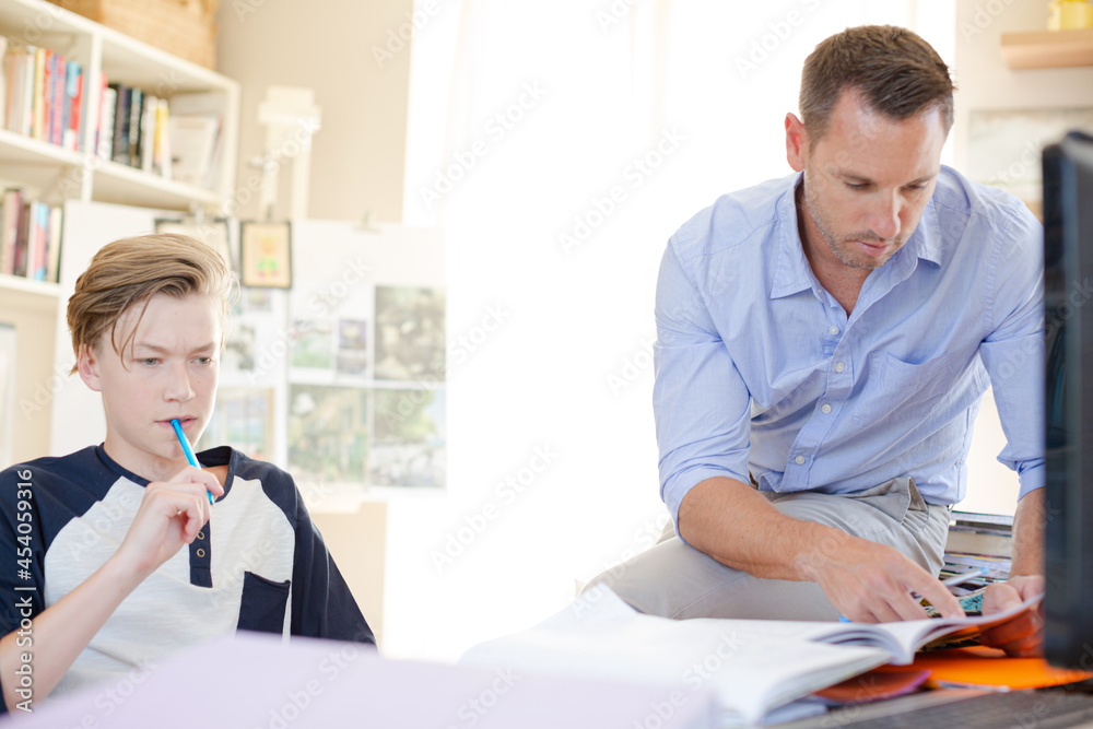 Obraz premium Father helping teenage son doing his homework in room