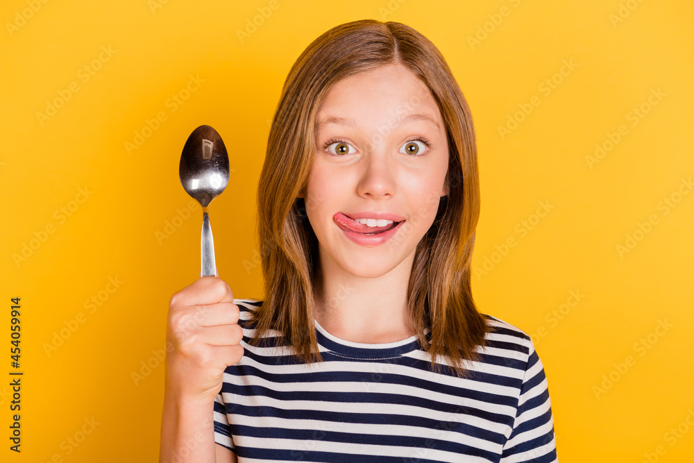 Photo of funny cheerful person arm hod spoon tongue out lick lip isolated on yellow color background Photo of funny cheerful person arm hod spoon tongue out lick lip isolated on yellow color background