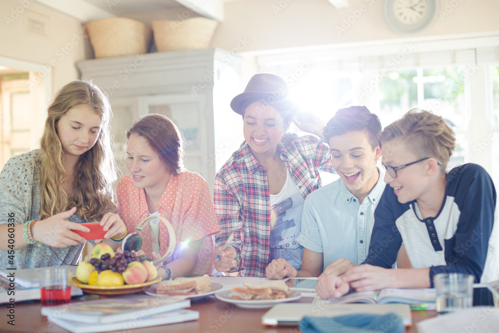 Group of smiling teenagers gathered around table in dining room Group of smiling teenagers gathered around table in dining room