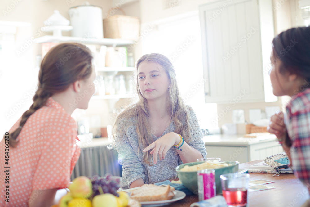 Teenage girls learning at table in kitchen