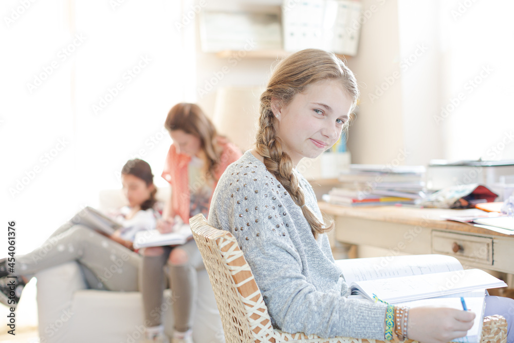 Three teenage girls doing homework in room Three teenage girls doing homework in room