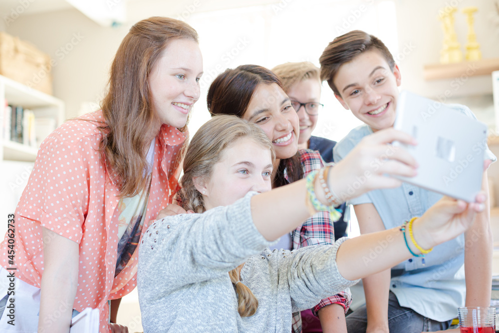 Group of teenagers taking selfie with digital tablet