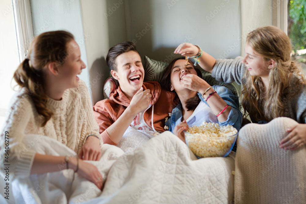 Group of teenagers throwing popcorn on themselves on sofa Group of teenagers throwing popcorn on themselves on sofa