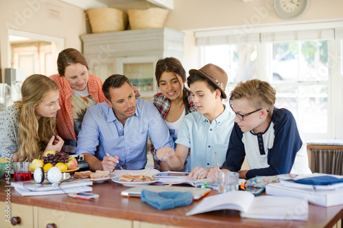 Teenagers with mid adult man sitting at table in dining room