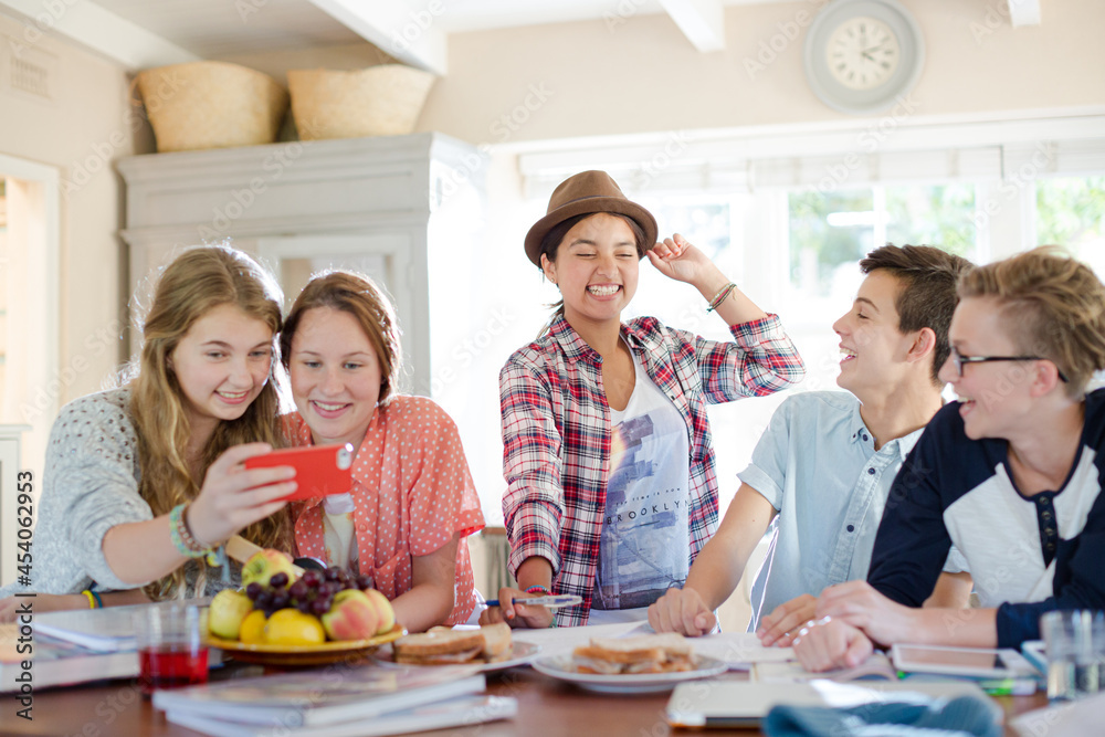 Group of smiling teenagers gathered around table in dining room Group of smiling teenagers gathered around table in dining room