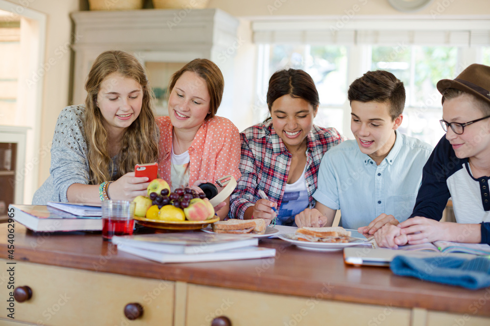 Fototapeta premium Group of smiling teenagers gathered around table in dining room