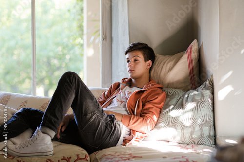 Teenage boy lying on sofa and thinking photo