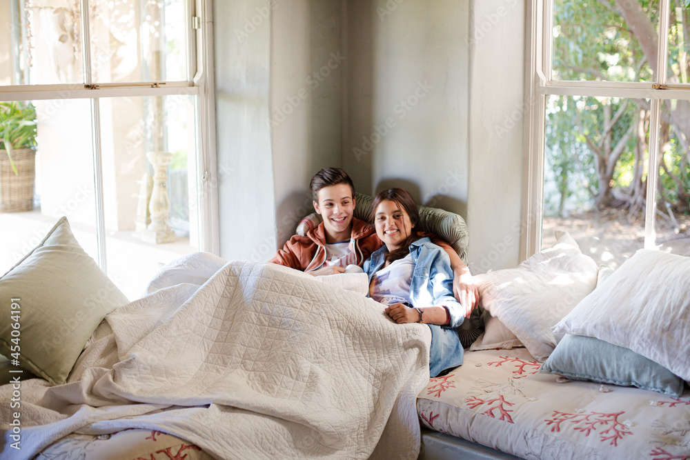 Fototapeta premium Teenage couple lying in bed and watching tv