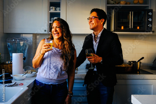 Mother and son enjoying drinks in kitchen. Cheerful mature woman enjoying drink with son while standing in kitchen at home