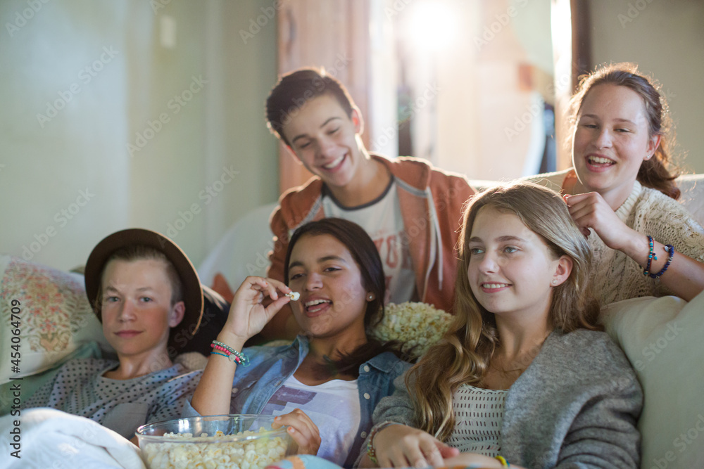 Obraz premium Group of teenagers having fun while watching tv on sofa