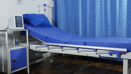 Close view of blue color hospital bed with blue curtains behind photo