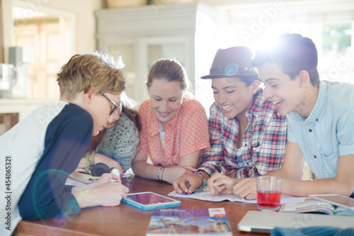 Group of teenagers using together digital tablet at table in kitchen