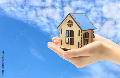 Wooden house in the palm of your hand, property sale concept