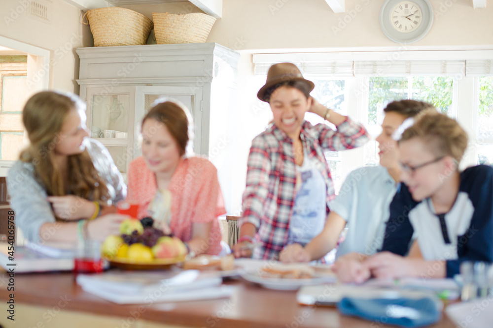 Fototapeta premium Group of smiling teenagers gathered around table in dining room