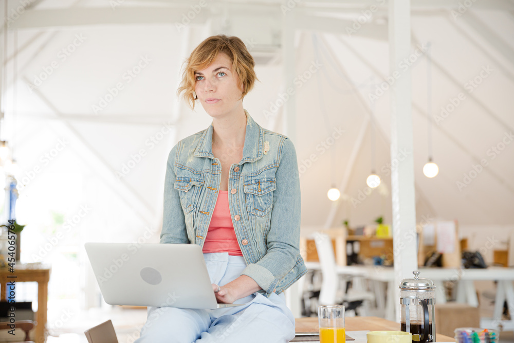Portrait of woman sitting at desk with laptop in office Portrait of woman sitting at desk with laptop in office