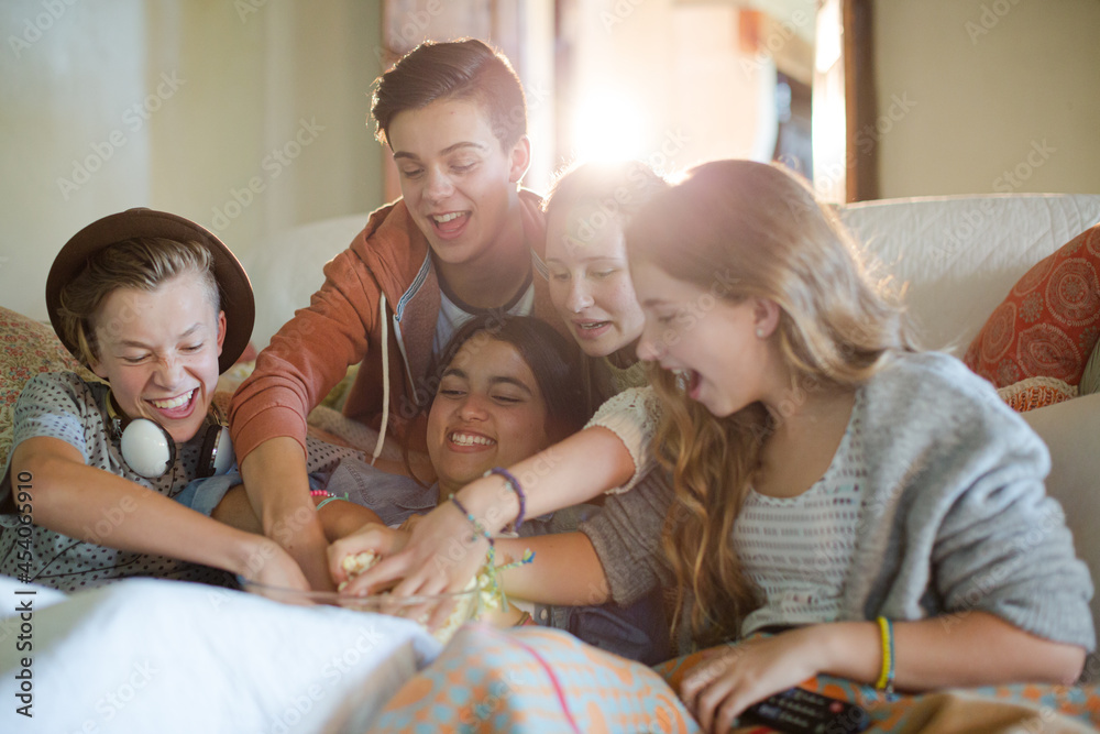 Group of teenagers throwing popcorn on themselves while sitting on sofa