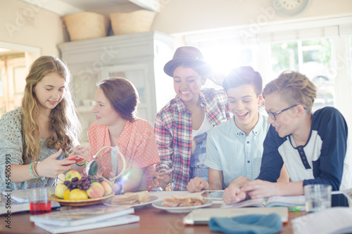 Group of smiling teenagers gathered around table in dining room